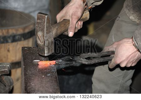 Blacksmith working metal with hammer on the anvil in the forge