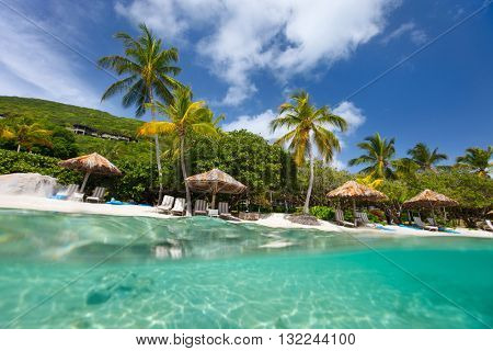 Beautiful tropical beach with palm trees, white sand, turquoise ocean water and blue sky at British Virgin Islands in Caribbean