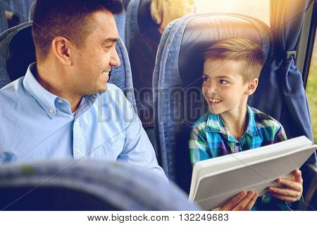 travel, tourism, family, technology and people concept - happy father and son with tablet pc computer sitting in travel bus