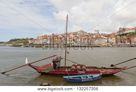 PORTO PORTUGAL - MAY 25 2016: Traditional Rabelo boat (used for port wine transportation) on Douro River in Porto Portugal. Historical part of Porto city (UNESCO site) at the background