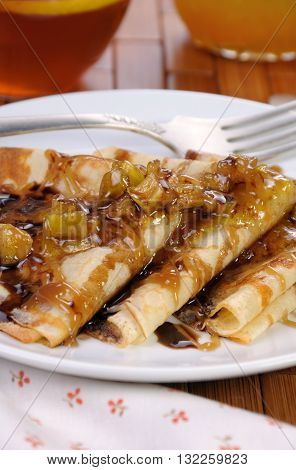 Breakfast pancakes on apples with caramel and chocolate and cup of tea