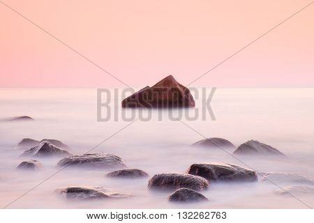 Romantic Morning At Sea. Big Boulders Sticking Out From Smooth Water Level. Pink Horozon With First