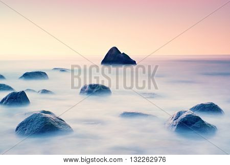 Romantic Morning At Sea. Big Boulders Sticking Out From Smooth Water Level. Pink Horozon With First