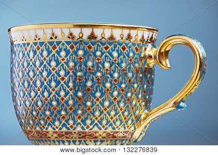 Thai fine art traditional five colors (Bencharong) tea cup over blue blurry background.
