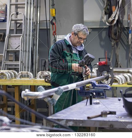 Industrial operator setting  computer controlled process of orbital welding machine in  stainless steel pipes manufacturing workshop.