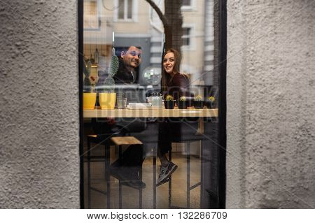 Happy couple have fun in cafe through wondow