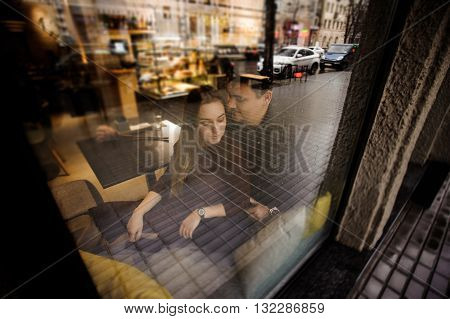 Happy couple have fun in cafe through wondow