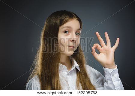 Happy girl. Closeup Portrait of handsome teen in casual shirt smiling show Ok on grey background.