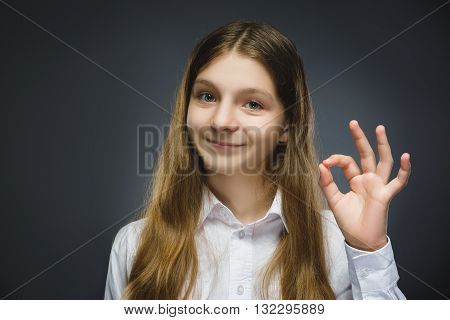 Happy girl. Closeup Portrait of handsome teen in casual shirt smiling show Ok on grey background.