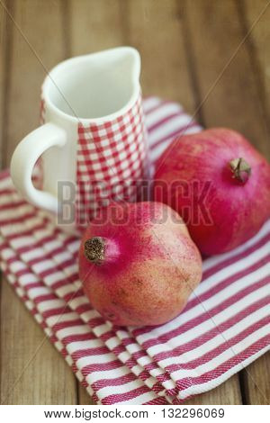 Red pomegranate and jug on wooden table