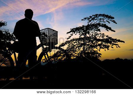 Silhouette Middle-aged Man  Exercise By Bicycle In Twilight Time.