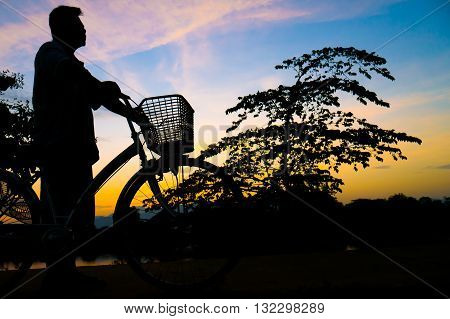 Silhouette Middle-aged Man  Exercise By Bicycle In Twilight Time.
