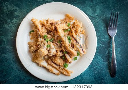 Plate of crispy calamari rings appetizer on green marble table
