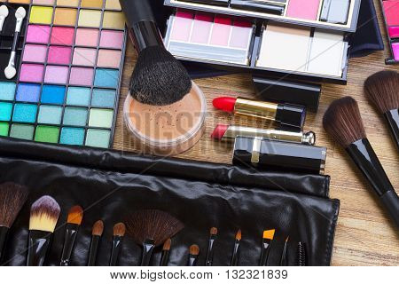 Set of professional brushes, lipsticks, maskara, eye shadows and powder on desktop, top view