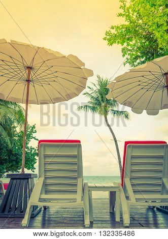 Beautiful beach chairs with umbrella around outdoor swimming pool neary sand and sea