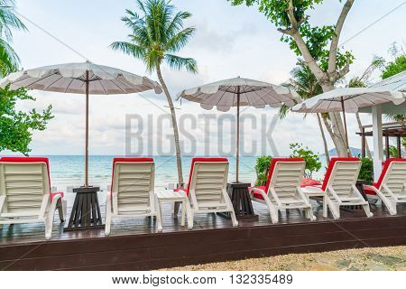 Beautiful beach chairs with umbrella around outdoor swimming pool neary sand and sea