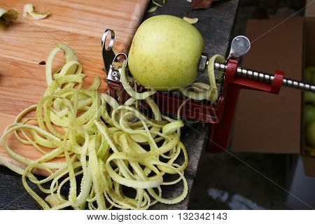 Whole yellow apple on hand-cranked apple peeler with peels
