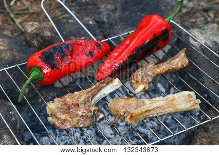 Grilled pork steaks on the grill. Lamb chops on grill with red peppers.
