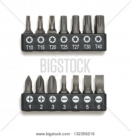 Various bits in a row in the bit holder. Bits for screwdrivers on the white surface. Cross bits. Flat-blade bits. Screw and unscrew fasteners. Cut-out object.
