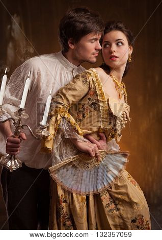 Lover couple. Man and woman standing on a stone wall background. Love relationship in a pair of man and woman. Images of the novel about love. Woman dreams. Man's instinct. Passionate, kissing, hugs.