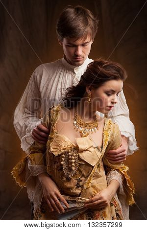 Lover couple. Man and woman standing on a stone wall background. Love relationship in a pair of man and woman. Images of the novel about love. Woman dreams. Man's instinct. Passionate, kissing, hugs.