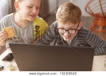 two boys play on a laptop boy t-shirt happy boy playing on a computer laptop, two brothers work there playing on the computer