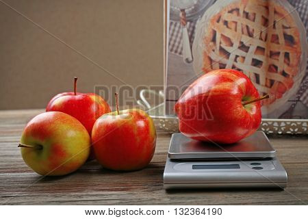 Apples with digital kitchen scales on wooden table. Cooking apple cake concept