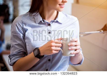 Make a pause. Pleasant delighted charming woman holding cup and drinking coffee while resting