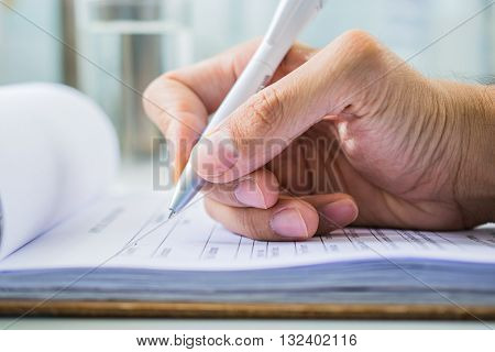 Hand with pen over application form on blure water glass background