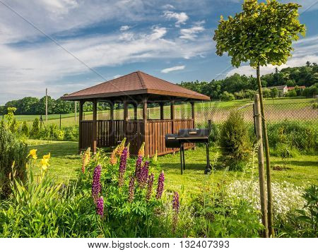 Wooden summer house with grill in the backyard