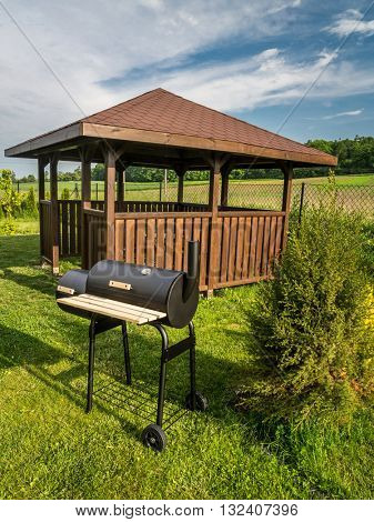 Wooden summer house with grill in the backyard