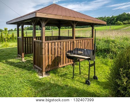 Wooden summer house with grill in the backyard