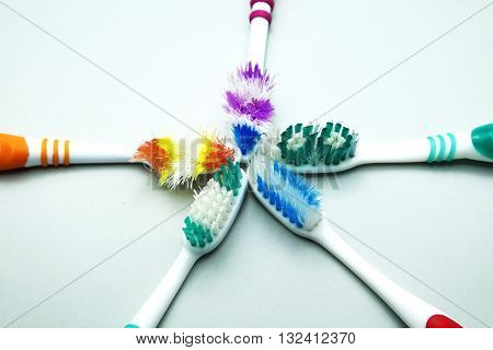 Five old colorful toothbrushes on gray background.