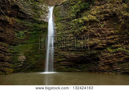 Beautiful landscape with forest waterfall and lush foliage in autumn