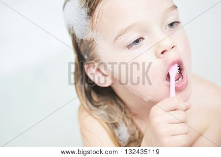Dental hygiene. Close up of little girl brushing her teeth. Fun in the bath