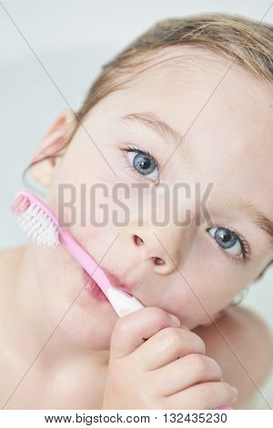 Dental hygiene. Close up of little girl brushing her teeth. Fun in the bath