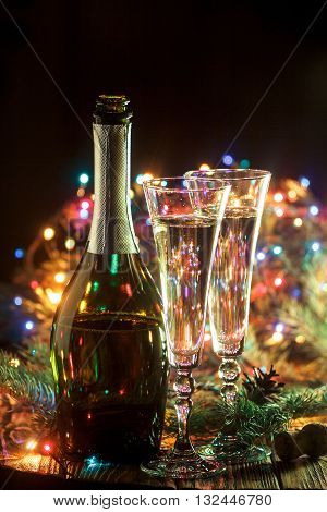 Open bottle of champagne and 2 full glasses in holiday setting. Celebration with Champagne. Christmas or New Year's holiday celebration concept.