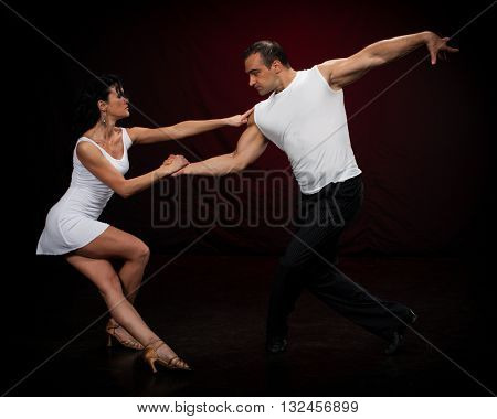 Dancing young couple on a dark background.
