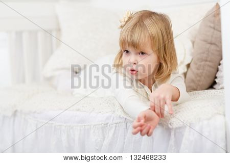 Resentful pretty little girl lies on a sofa in the room.