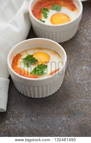 Eggs baked with tomatoes and parsley in the ramekins vertical