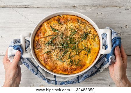 Moussaka with rosemary in the ceramic pan in the hand top view
