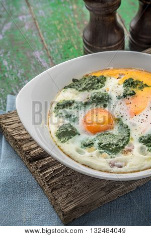 Florentine eggs with pureed spinach on the wooden table vertical