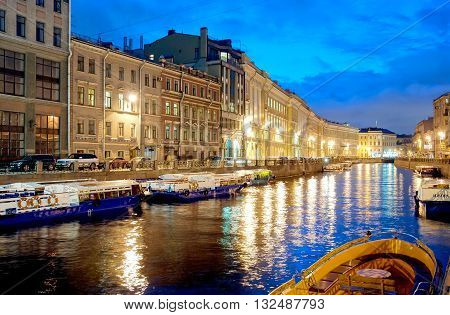 SAINT-PETERSBURG, RUSSIA - APRIL 21, 2016: Excursion boats on the Moika River near The Nevsky Avenue and The Green Bridge. On the background is The Pevchesky Bridge. Night view.