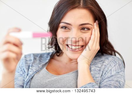 pregnancy, fertility, maternity, emotions and people concept - happy smiling woman looking at pregnancy test at home