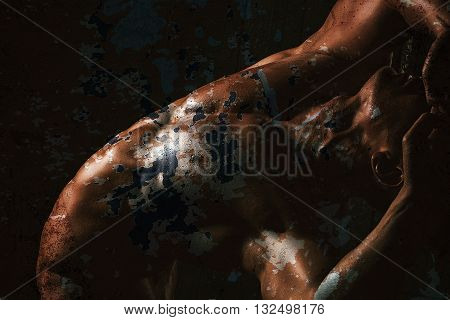 Handsome young flexible man with sexy bare muscular torso combined with textured painted old wall peelling off double exposure