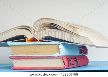 Open book stack of colorful hardback books on light table. Back to school. Copy space for text. Toned image.