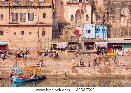 MADHYA PRADESH. INDIA - DEC 27. 2015: People walking near river bank of old indian city with rustic indian houses and riverboats on December 27, 2015 in India. Population of Chitrakoot is 22294 people