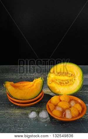 Fresh cantaloupe melon and ice on dark background copy space hot summer concept
