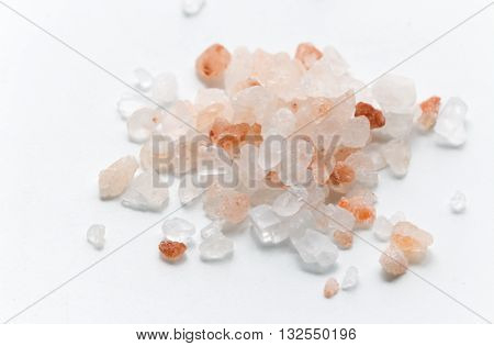 Pink Himalayan salt. Himalayan salt pile on white background. Pink crystal salt  isolated on white background. Close up Himalayan salt - pink and orange coarse crystals.