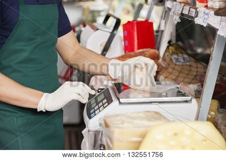 Salesman Weighting Cheese On Weight Scale